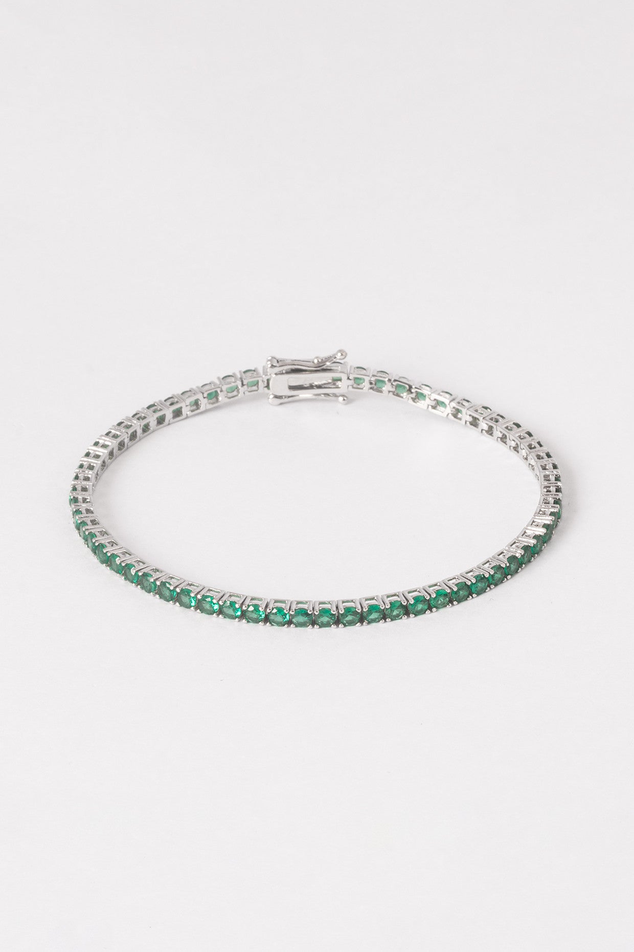 Silver bracelet with green gemstones on a white background